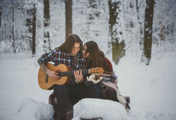 Pareja tocando la guitarra en la nieve. Cuidar la guitarra