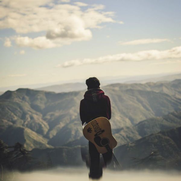 Hombre con guitarra devidamente cuidada de las temperaturas mirando el paisaje 