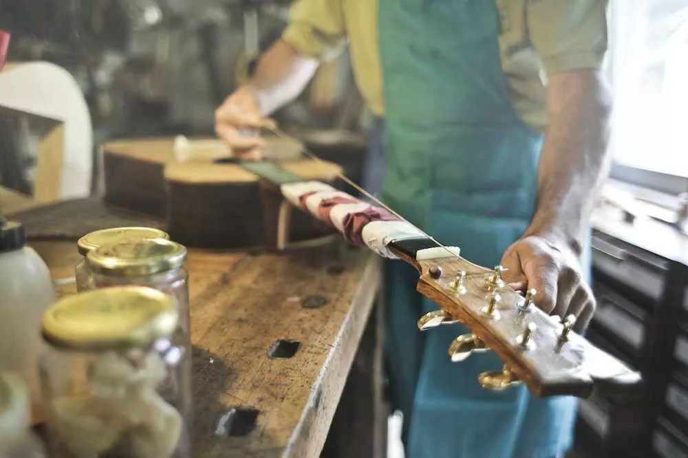 Un luthier arreglando una guitarra acústica