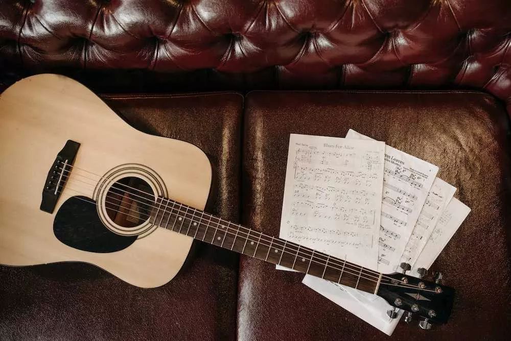 Una guitarra acústica y partituras en un sofá