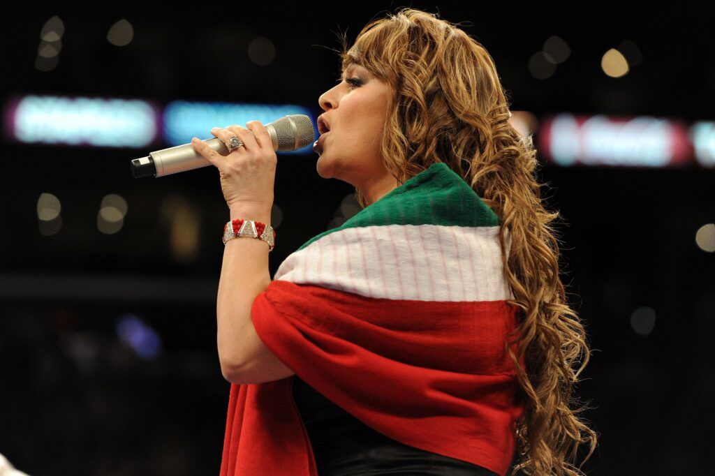 Jenni Rivera canta en show con la bandera mexicana alrededor suyo