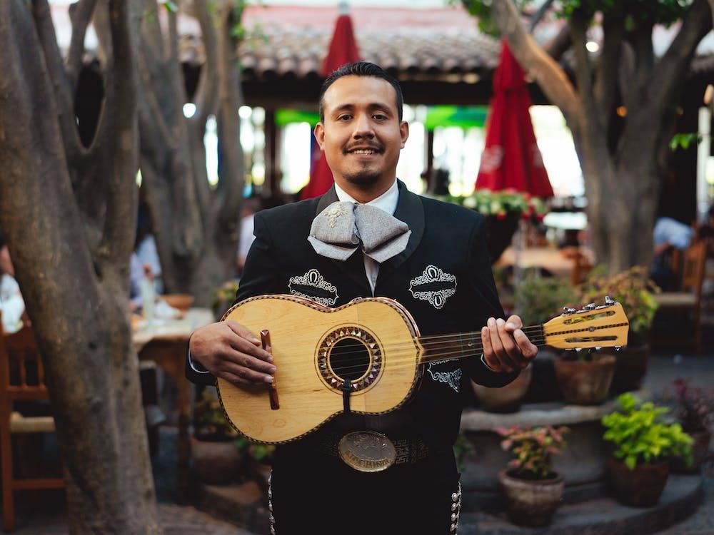 Hombre mariachi con una guitarra en las manos sonríe para la foto