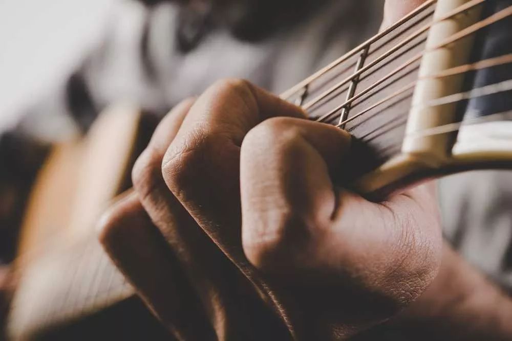 Mano toca canciones con 2 acordes en una guitarra acústica