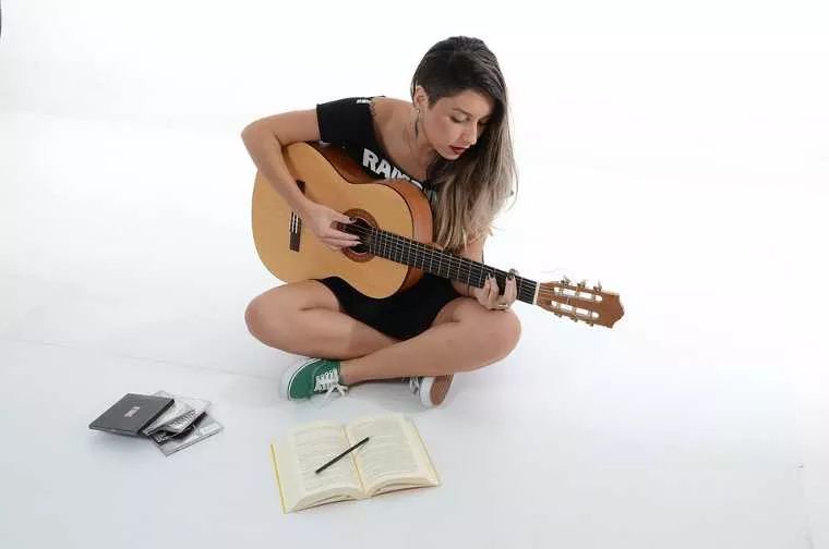 Mujer toca la guitarra con mala postura
