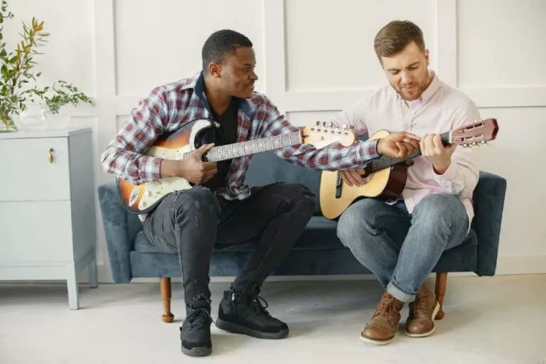 Dos hombres en un sofa aprendiendo técnicas de guitarra