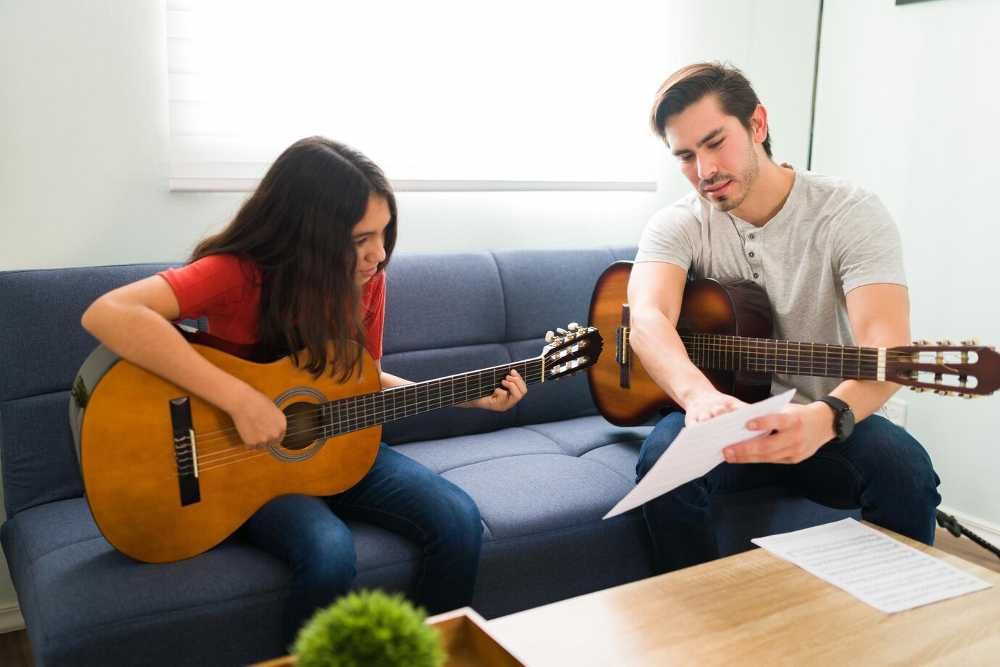 Profesor de música enseñando qué es una cifra a una alumna de guitarra