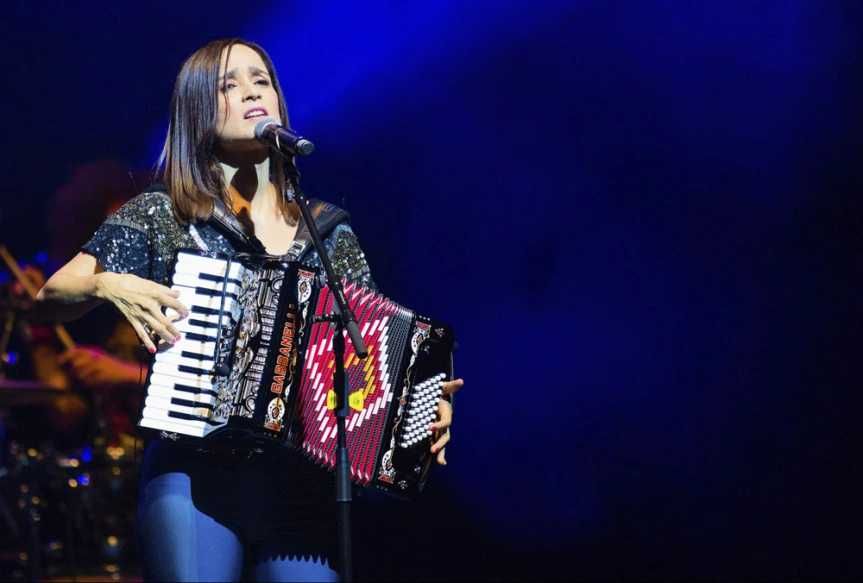 Julieta Venegas tocando el acordeón y cantando en un concierto