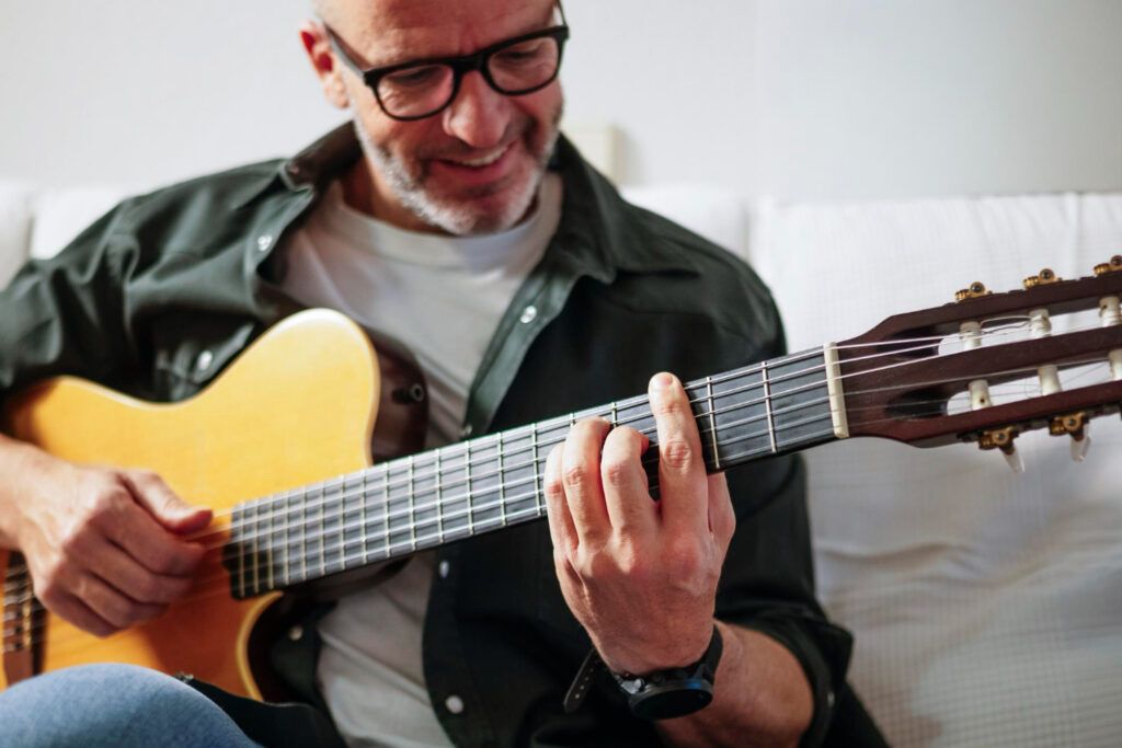 Hombre toca acordes de canciones en inglés en guitarra
