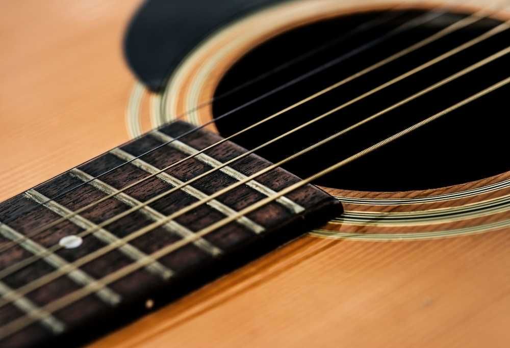Close de um violão com destaque para o final do braço e para o tampo do instrumento
