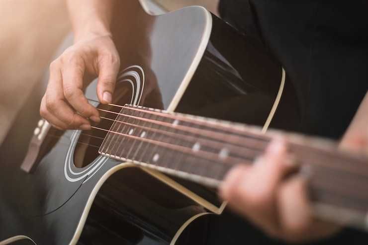 Músico tocando um violão preto