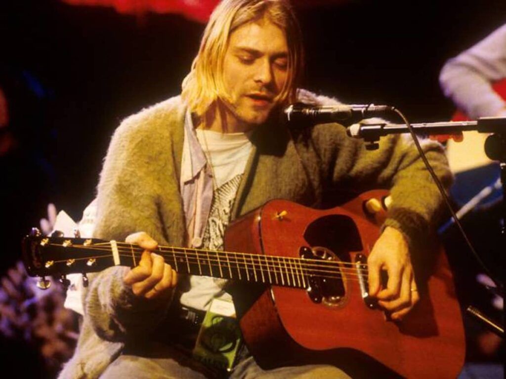 Kurt cobain tocando la guitarra y cantando al mismo tiempo
