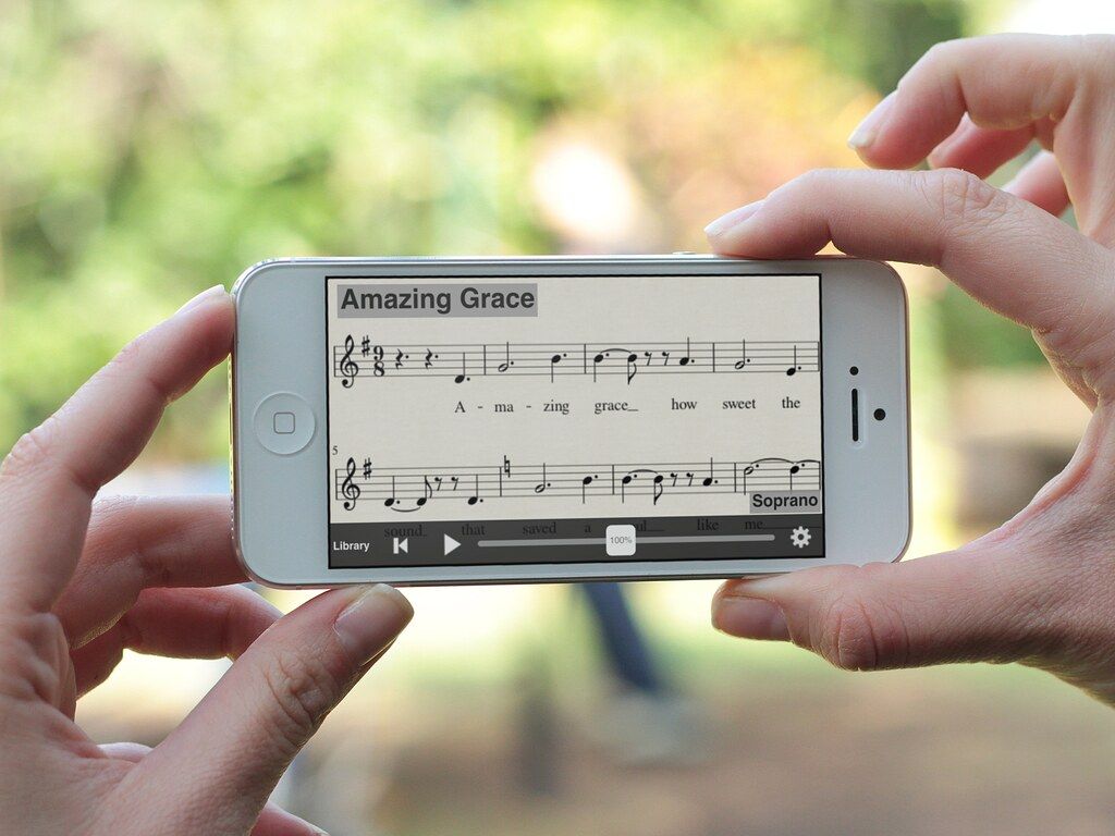 Mãos femininas seguram um telefone que funciona o MuseScore, um dos aplicativos de partitura mais completos