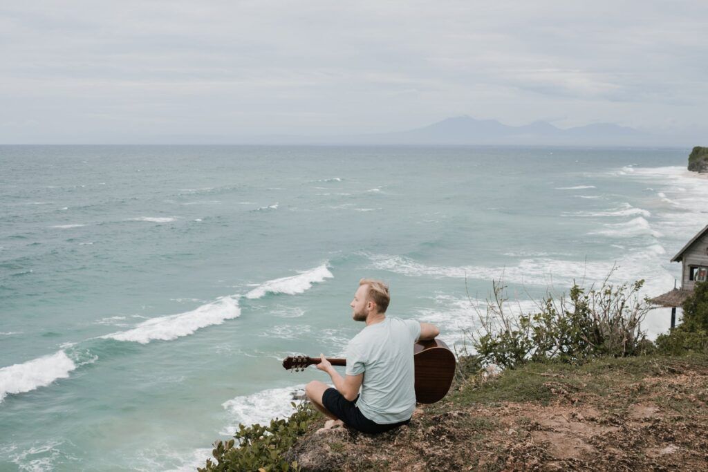 Músico toca violão de frente pro mar