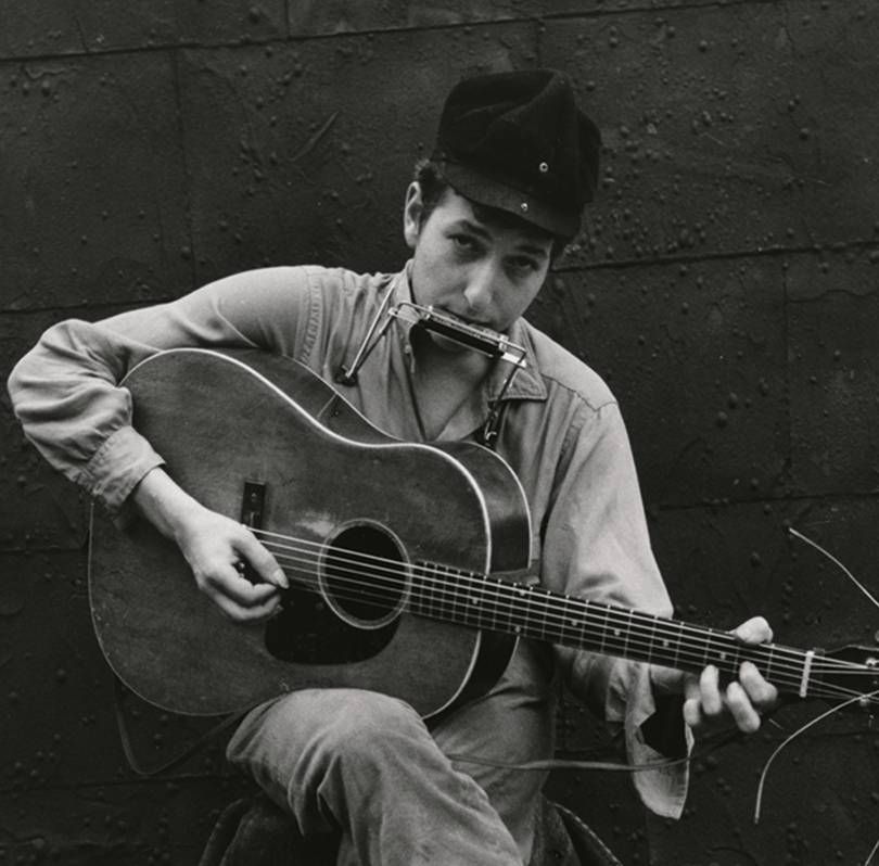 Um jovem Bob Dylan tocando violão e gaita