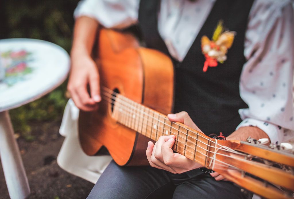 Músico sentado tocando músicas para casamento no violão