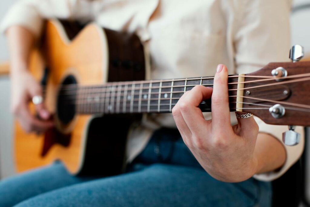 Mulher tocando músicas com pestana em um violão acústico e com cordas de aço