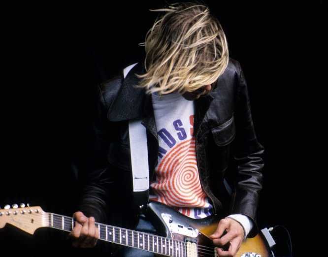 Kurt Cobain tocando guitarra, fazendo power chords e olhando para baixo