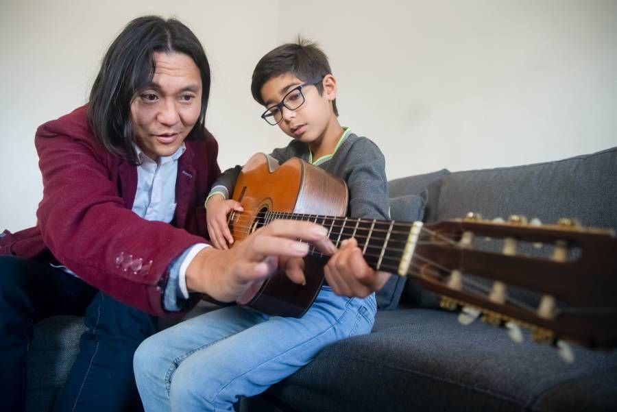 Professor ensina aluno a fazer acorde no violão