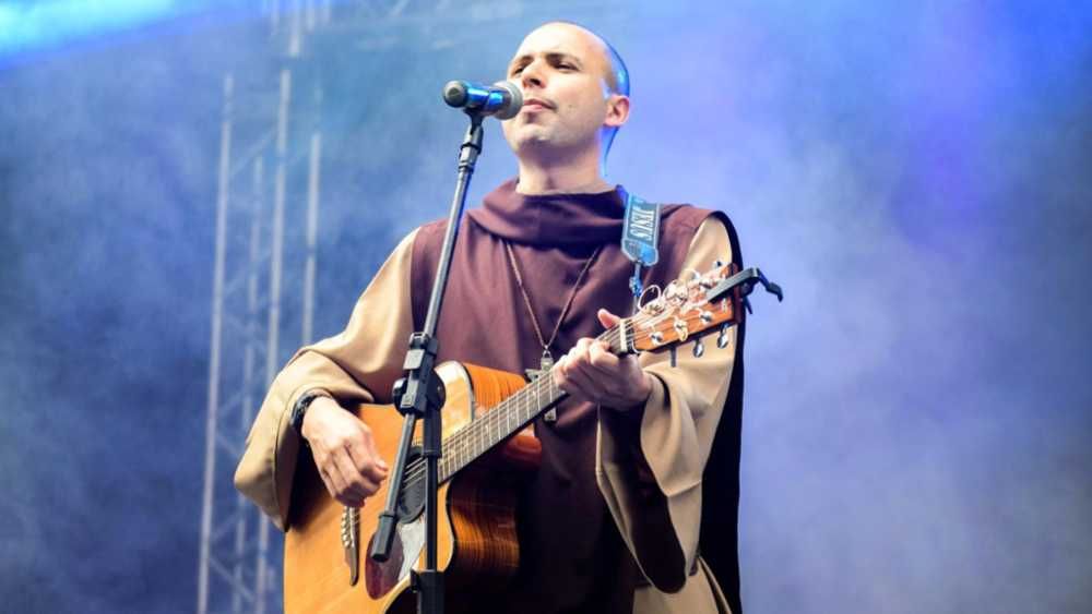 Frei Gilson tocando violão e cantando em show