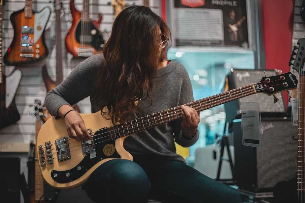 Musicista tocando baixo sentada em uma loja de instrumentos musicais