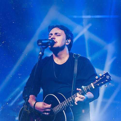 Theo Rubia cantando e tocando violão em show