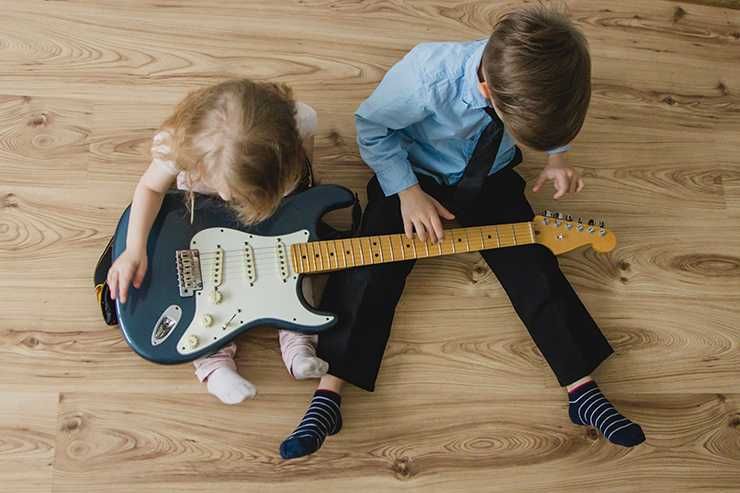 Duas crianças segurando uma guitarra