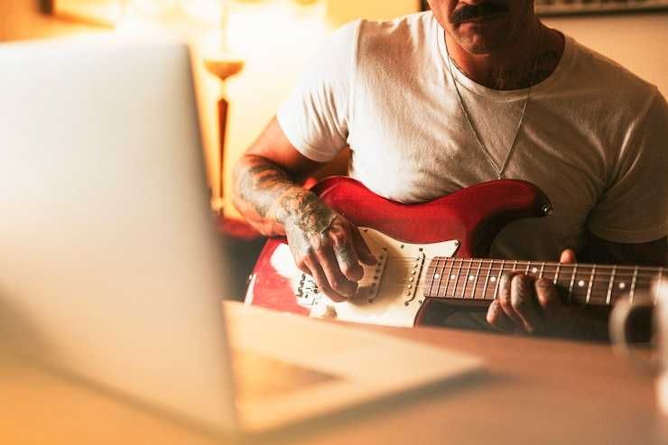 Homem estudando guitarra pelo computador