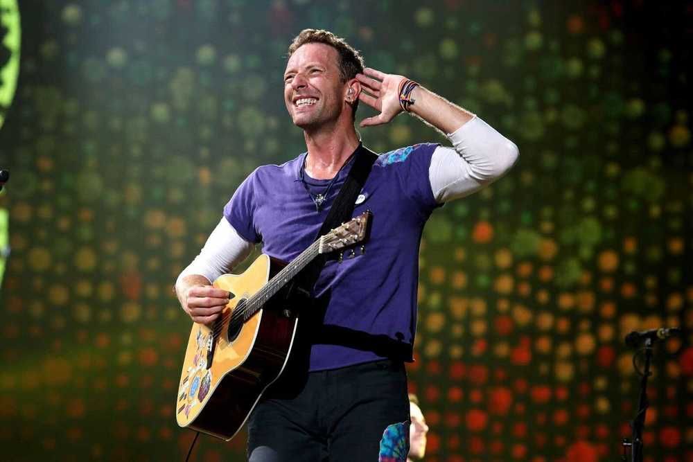 Chris Martin com seu violão empolgado com o público em show do Coldplay