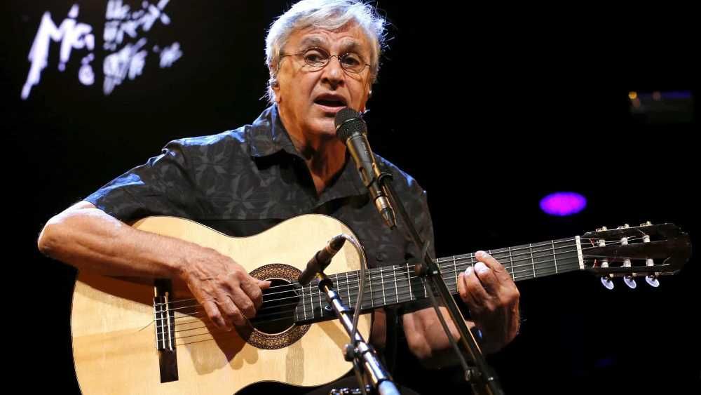 Caetano Veloso tocando violão e cantando em show