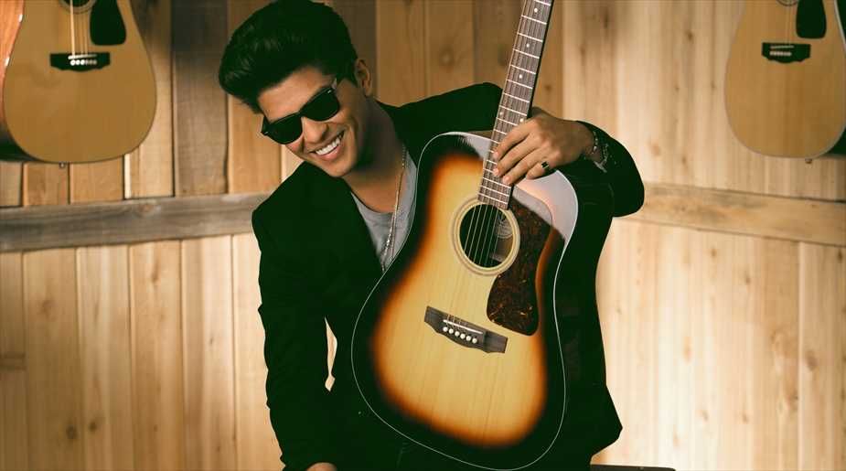 Bruno Mars segurando seu violão em estúdio