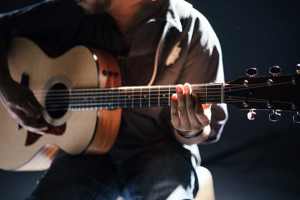 Músico tocando violão montando um acorde de Ré com sétima maior