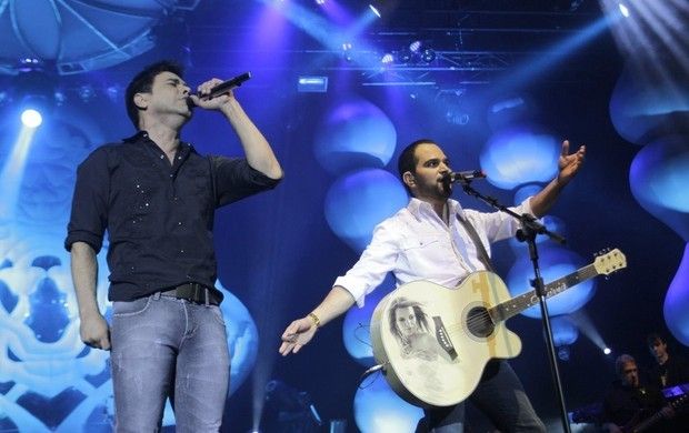 Zezé Di Camargo cantando e Luciano tocando violão e cantando em show
