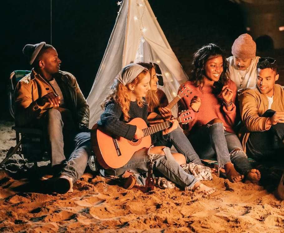 Amigos tocando violão na praia em um luau