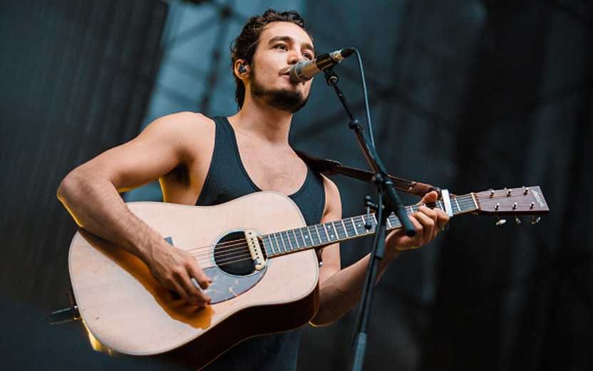 Tiago Iorc tocando violão e cantando em show