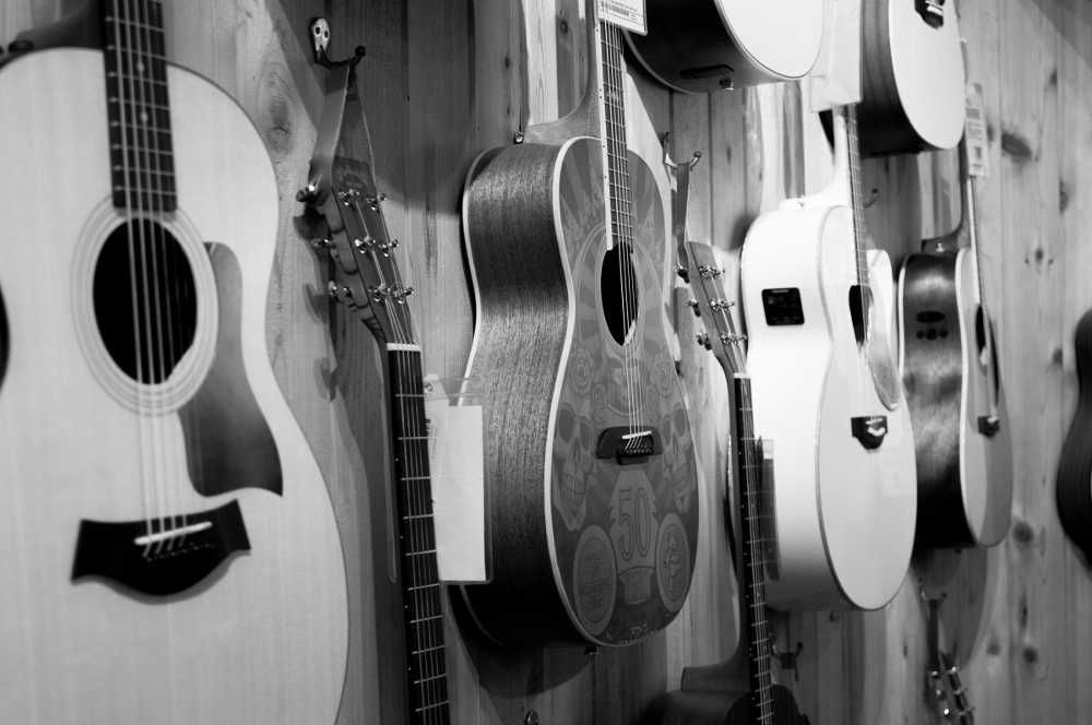 Vários modelos de violão pendurados em parede de loja de instrumentos