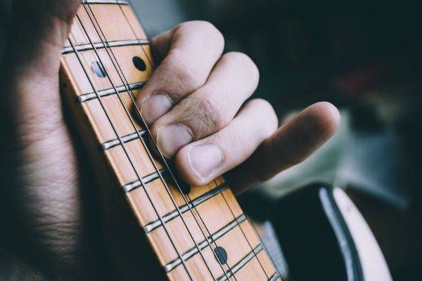 Dedos de um músico na guitarra