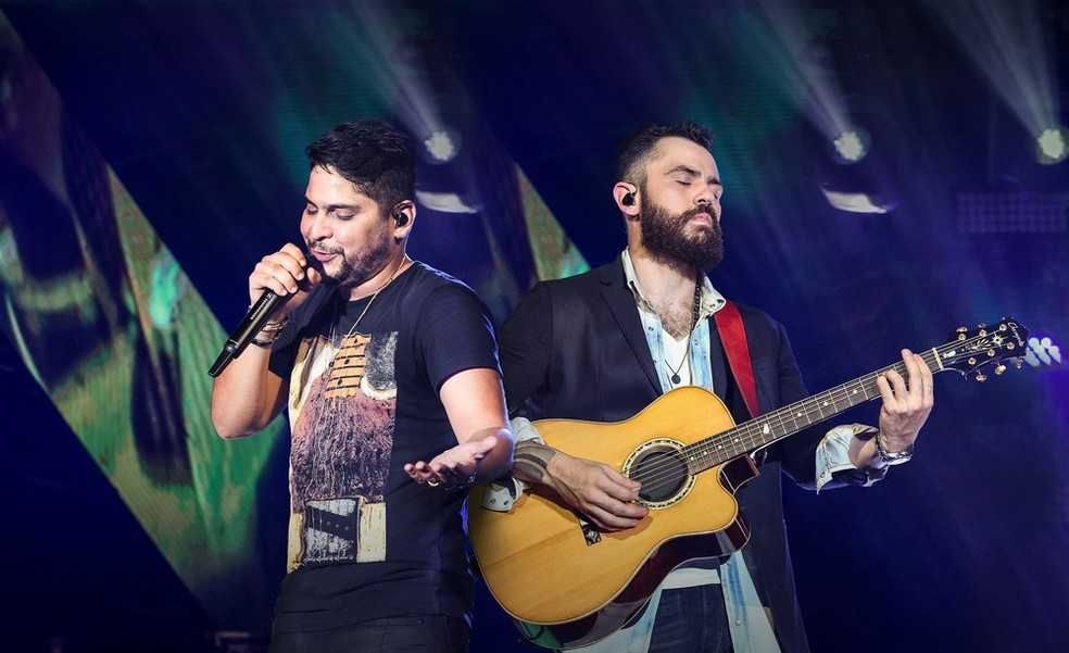 Jorge cantando e Mateus tocando violão em show da dupla