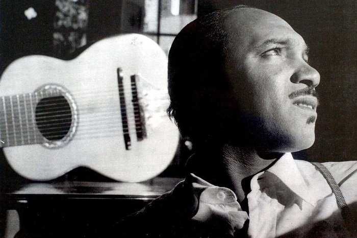 Lupicínio Rodrigues olhando para cima com um violão no fundo