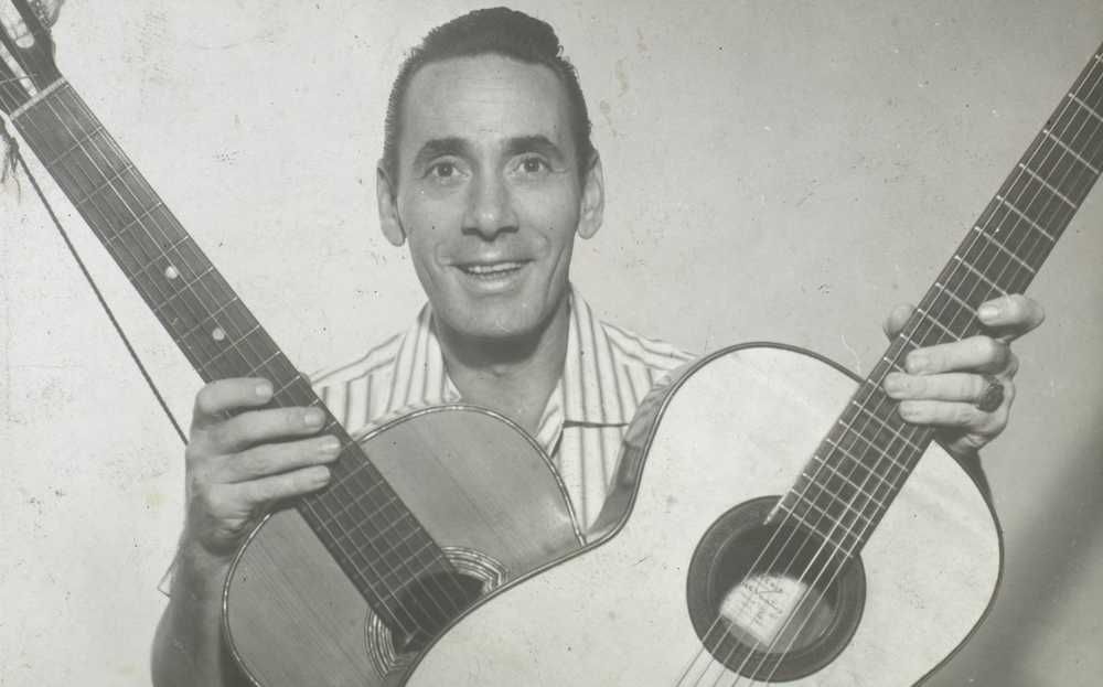 Nelson Gonçalves segurando dois violões cruzados e sorrindo