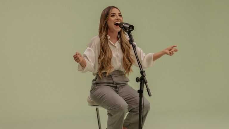 Gabriela Rocha cantando sentada com os braços abertos