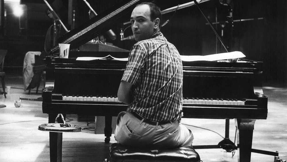 João Donato olhando para trás sentado em frente a um piano