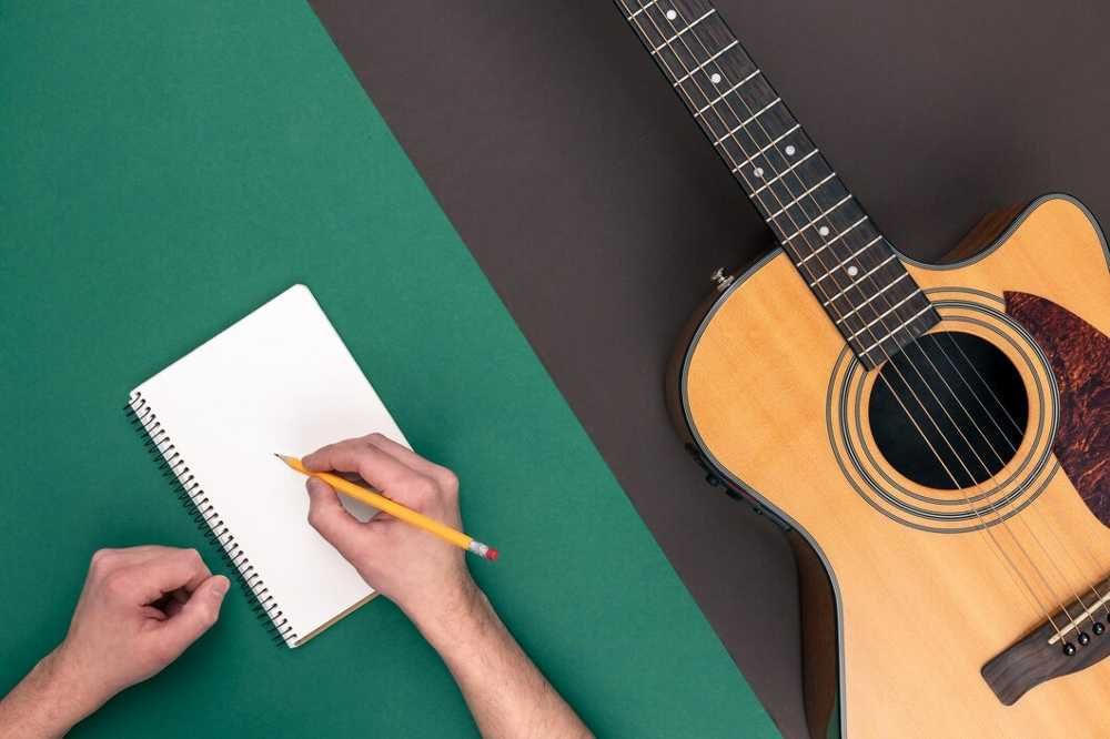 Estudante de música escrevendo em um caderno com um violão ao lado