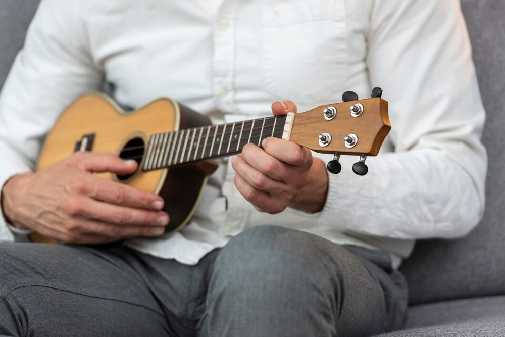 Homem tocando ukulele sentado em um sofá