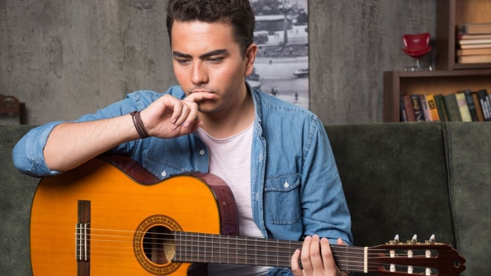 homem pensativo com violão - intervalos musicais