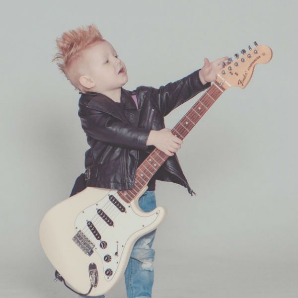 Menino vestido de roqueiro e tocando guitarra