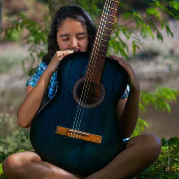Menina de olhos fechados segura um violão