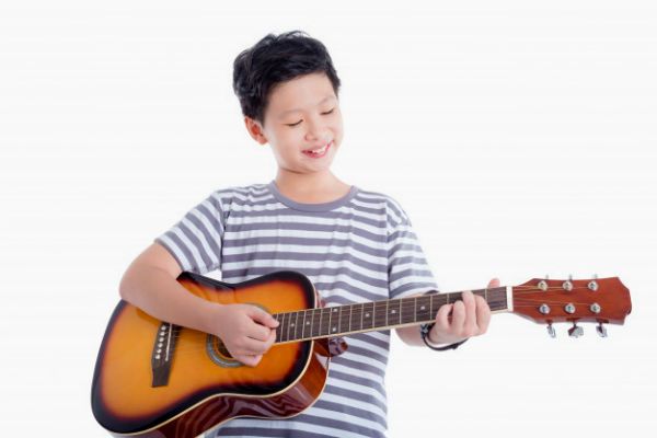 Menino asiático tocando violão
