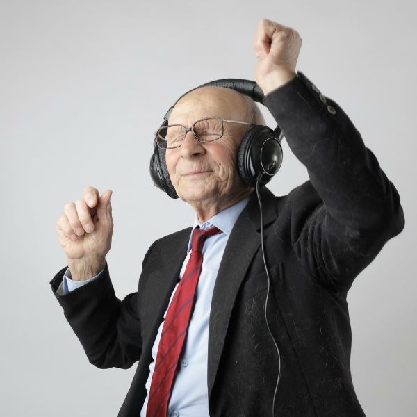 Homem idoso usa terno e ouve música com fones de ouvido