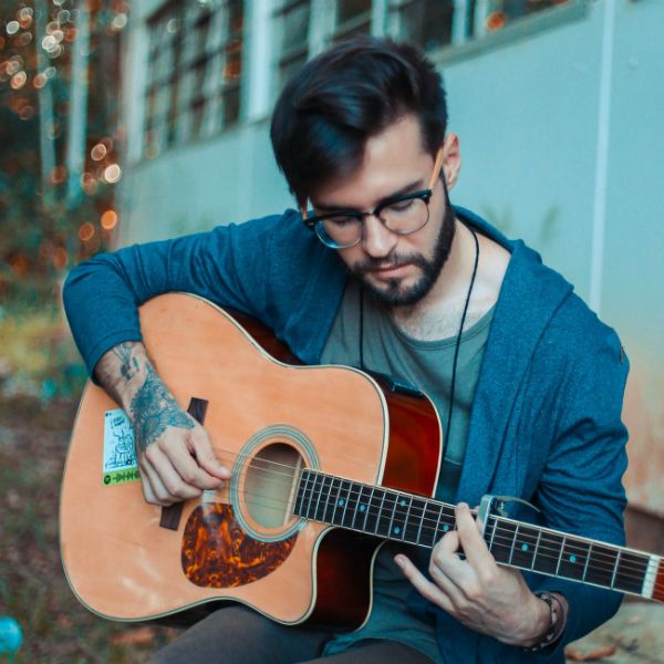 Joven tocando la guitarra acústica con dedicación