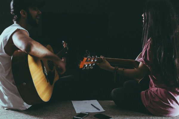 Rapaz e moça tocam violão